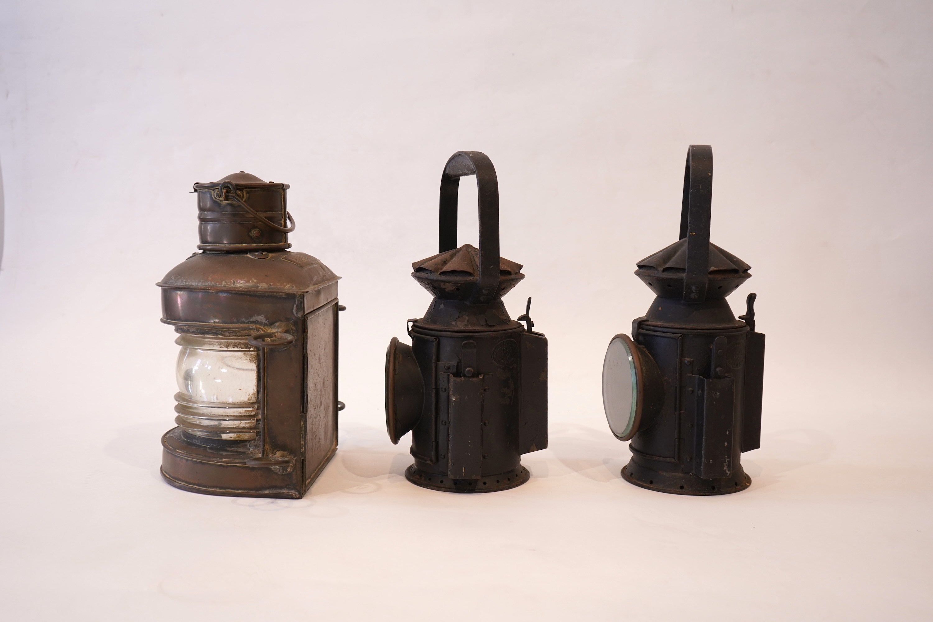 Two black painted railway hand lamps by Pratt & Co. Ltd. Birmingham, both dated 1945, both with burners and reflections, one intended for three colour aspect, with one glass missing, together with a brass ship’s bulkhead